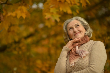 Senior woman walking in the park in autumn.の写真素材