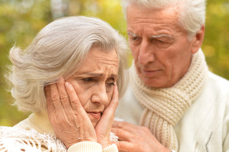 Portrait of sad senior couple in autumn park