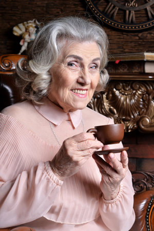 Portrait of senior woman with coffee in chairの写真素材