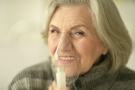 Elderly woman is sick and uses an inhalerの写真素材