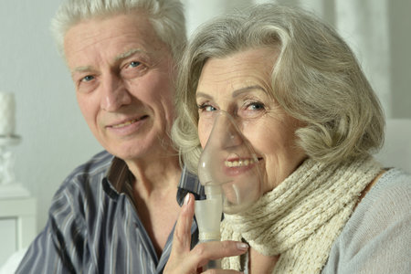 An elderly couple is sick and uses an inhalerの写真素材