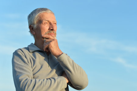 Portrait of a serious senior man on sky background.の写真素材