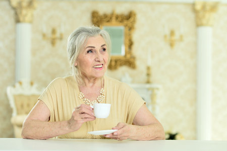 Beautiful elderly woman drinking coffee at homeの写真素材