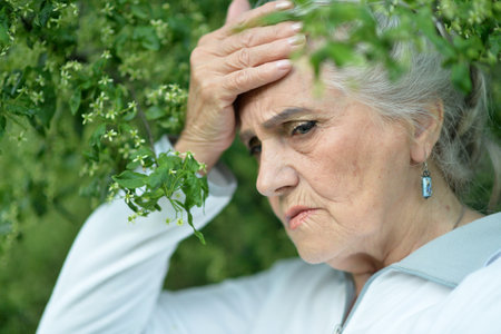 Portrait of senior sad woman in parkの写真素材