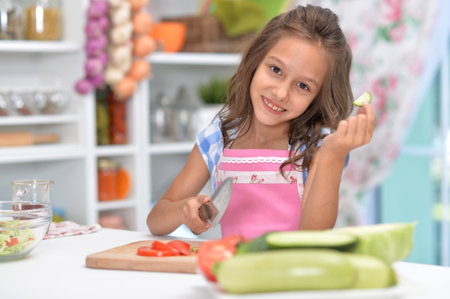 Cute happy girl coocking salad on kitchenの写真素材