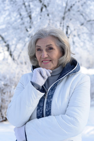 Beautiful elderly woman posing in a snowy winter parkの写真素材