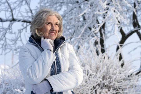 Beautiful elderly woman posing in a snowy winter parkの写真素材