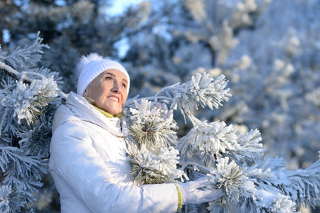 Beautiful elderly woman posing in a snowy winter parkの写真素材