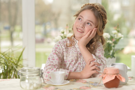 Smiling little girl holding big cup of teaの写真素材