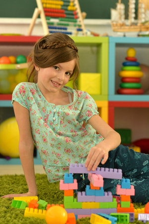 Portrait of cute girl playing with colorful plastic blocks in roomの写真素材