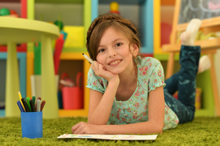 girl in the nursery draws lying on the carpet.の写真素材