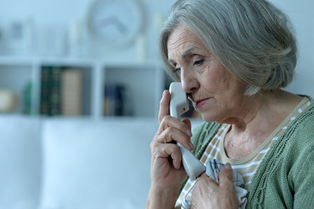 Elderly Woman on Phone in Cozy Roomの写真素材