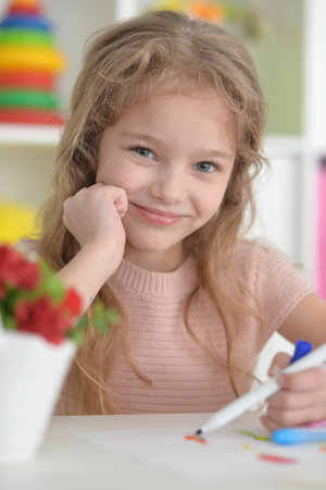 cute girl in the nursery draws at the tableの写真素材