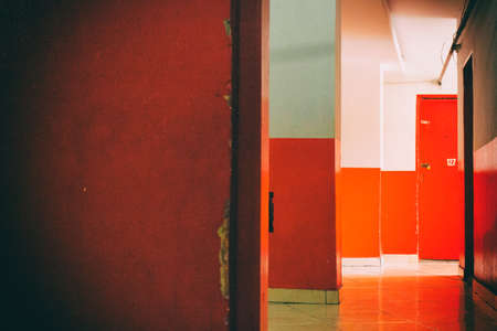 Red and white corridor with red door and the sun light at the end of it. No people.の写真素材