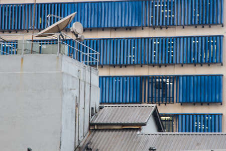 Old business building with satellite antenna on top and blue windows huge office building on the background.の写真素材