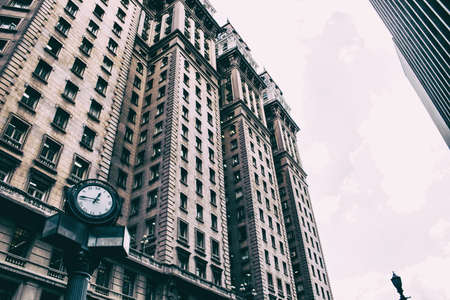 Low angle view of an old business building with a clock on the street in front of it.の写真素材