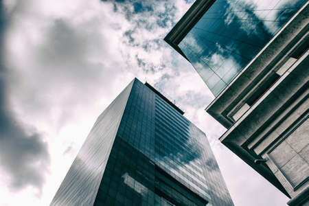 White clouds are reflected in the windows of business buildings made of glass.の写真素材
