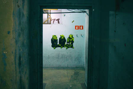 Ruined blue wall with the three wise monkeys sticker on a worn occupied building.の写真素材