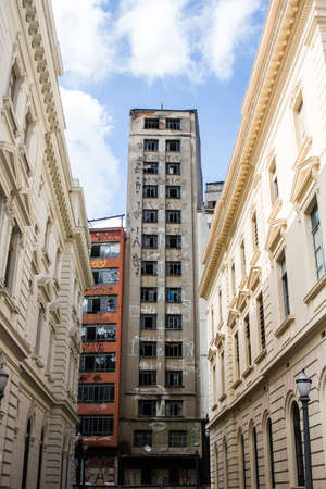 Abandoned grey and red buildings at the end of a corridor made by classic architecture white constructions.の写真素材