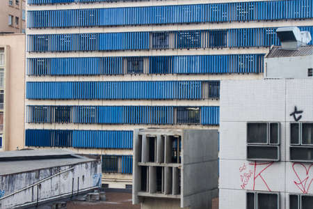 Blue windows building facade with old and graffiti painted buildings on front of it in downtownの写真素材