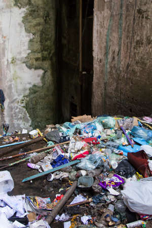 Trash in an occupied residential building near a dangerous deep empty elevator hole in an abandoned building occupied by social housing movement.の写真素材