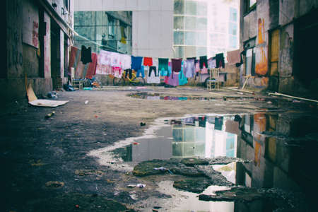 Hanged clothes in a condemned complex of abandoned buildings used by a social housing movement with an office building in the background.の写真素材