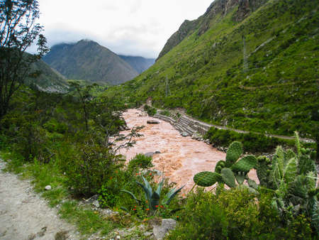 Urubamba River water flow near Ollantaytambo village in the Sacred Valley of south Peru, region with massive Inca fortress with large stone terraces on a hillside.の写真素材