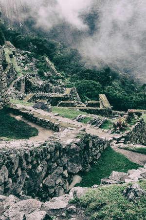 Vertical image of Machu Picchu stone ruins with low clouds on the nature on the background. Peru. South America. No people.の写真素材
