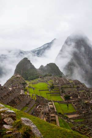 Verical classic view of the ancient mysterious city of Machu Picchu with intense clouds covering the...