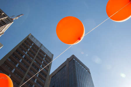 Orange balloons are hanged by a wire in front of blue sky.の写真素材