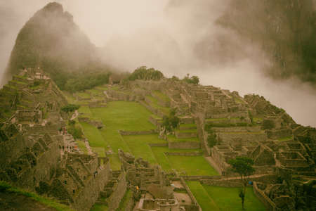 Classic view of the ancient mysterious city of Machu Picchu with intense clouds on the background in Peru. Astonishing wallpaper image.の写真素材