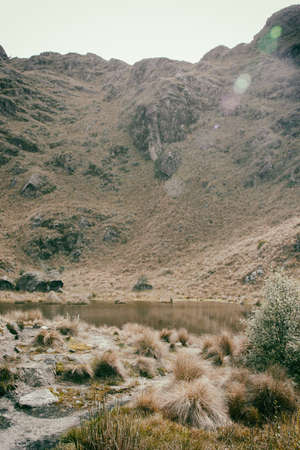 Serene lake on a valley in the Andes mountains surrounded by rocks and green and yellow fields. Peru. South America. No people.の写真素材