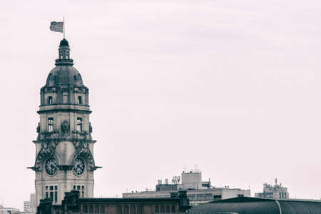 High clock tower with the flag of San Paolo state in Brazil and roofs of buildings of the surroundings with grey clouds on the background. No people.の写真素材
