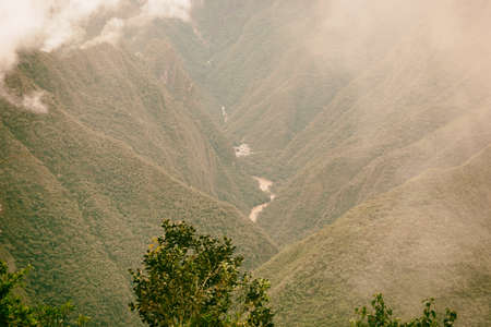 Serene red water river flow and a village on a valley in the Andes mountains in mist. Machu Picchu. Peru. No people.の写真素材