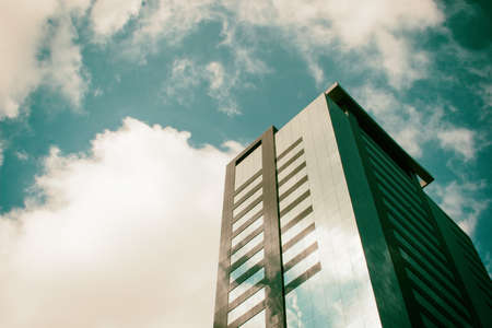 Low angle view of a corporate building with blue sky and clouds in the background surrounded by a golden ambience light.の写真素材
