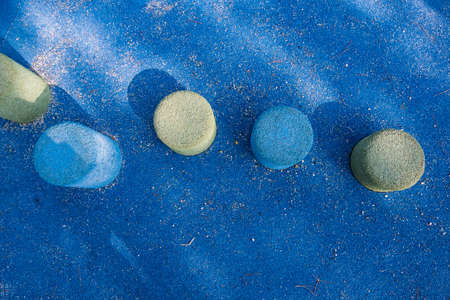 Wallpaper background of rubber blue and green cylinders on a kidâs playground with blue rough floor with tree shadows. No people.の写真素材