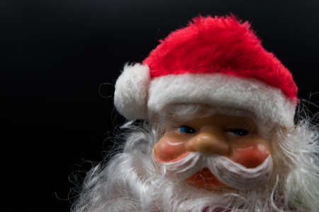 Holidays wallpaper background of Santa Claus toy with silver bell on his hand isolated on black background.の写真素材