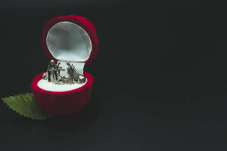 Christian nativity scene silver figures inside a red rose flower jewel velvet box isolated on black background.の写真素材