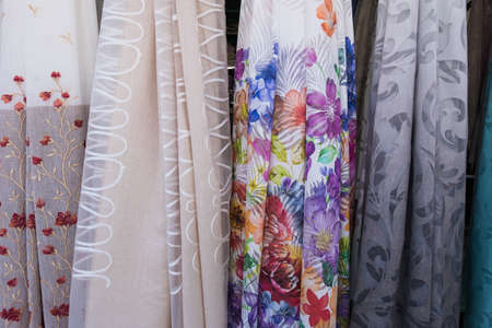 Wallpaper background of colorful woman dresses on hangers. No people.