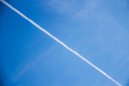Wallpaper background of an airplane white vapor trace in the blue sky on a summer afternoon. No...