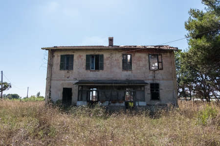 Grungy wallpaper background of worn abandoned house facade detail with wild nature on the surroundings with blue sky background. No people.の写真素材