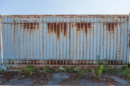 Industrial grungy wallpaper background of an automatic white metallic gate with rust on a summer day with blue sky in the background. No people.の写真素材