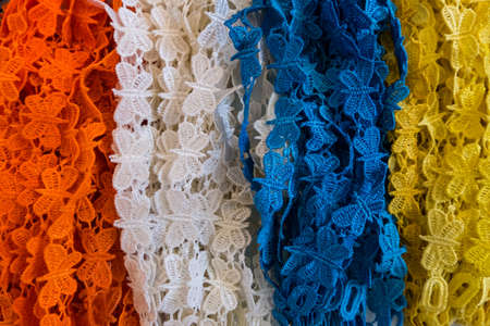 Wallpaper background of colorful options of fabric laces in orange, white, blue and yellow at a fashion store.の写真素材