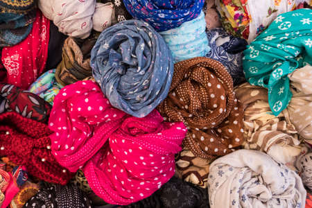 Wallpaper background of colorful women clothes and dresses made of many fabric and textures wrapped at a street store display basket. No people.の写真素材