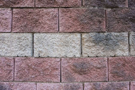 Wallpaper background texture of a wall made of big colorful red, grey, yellow and white worn bricks. Grunge background.の写真素材