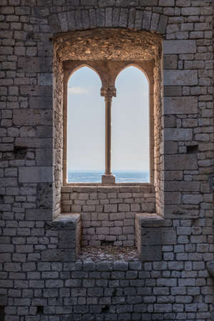Old vintage window on an ancient facade. Medieval, stone and steel facade with rusty window. No peopleの写真素材