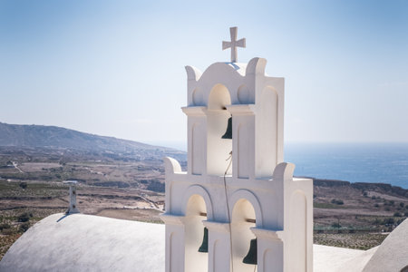 White church on a mountain with Santorini landscape on the backgroundの写真素材