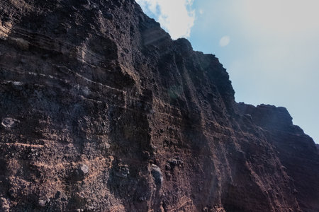 Red beach volcanic stone wall with cloudy skyの写真素材