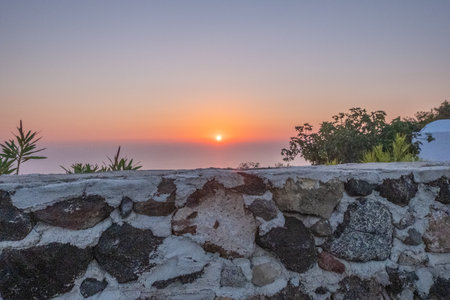 Sunset behind old rock wall of Santorini, Greece.の写真素材