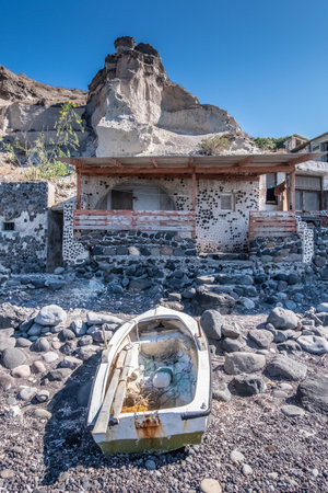 Warn fisherman boat and building on the Santorini beachの写真素材